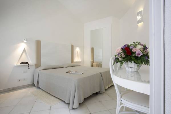 Schlafzimmer im Mare Pineta Hotel mit zwei Betten und einem Tisch mit Blumen