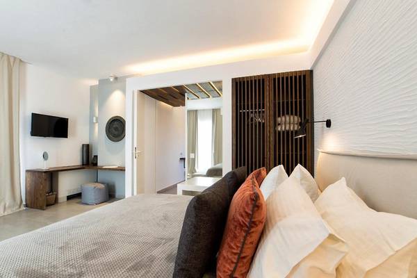 Schlafzimmer im Paros Agnanti Resort & Spa mit Bett, Fernseher und Deko-Elementen.