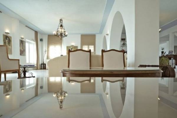 Innenbereich des Paros Agnanti Resorts und Spa mit hellen Wänden, einem Esstisch und Stühlen.