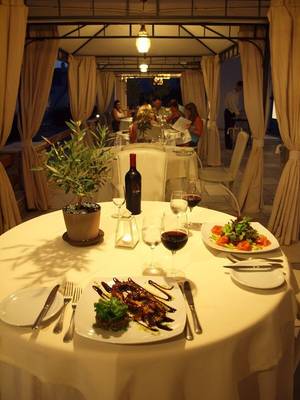 Abendessen unter einem Vordach im Paros Agnanti Resort und Spa mit Tisch, Essen, Wein und Pflanzen
