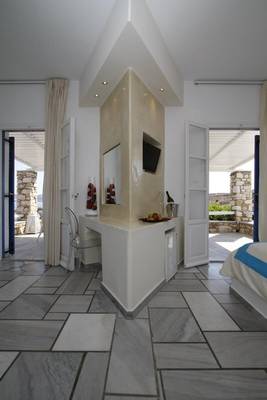 Innenbereich des Paros Agnanti Resorts & Spa mit einem Bett, einer Theke und einem Fernseher.