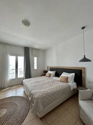 Schlafzimmer im Paros Agnanti Resort & Spa mit Doppelbett, Fenstern und Balkon.