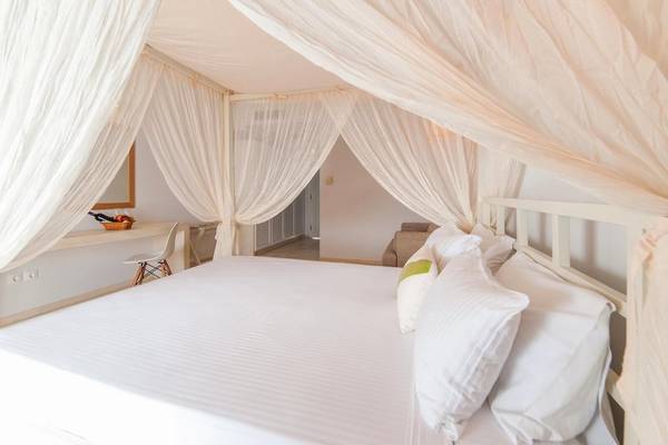 Luxuriöses Schlafzimmer im Paros Agnanti Resort & Spa mit einem großen Bett unter einem Baldachin.