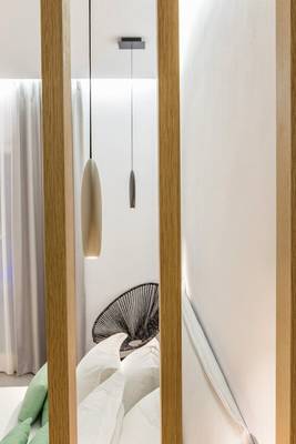 Innenansicht eines Schlafzimmers im Paros Agnanti Resort & Spa mit zwei Lampen und einem Bett.