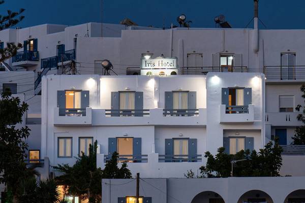 Außenansicht des Iris Hotels bei Nacht mit blauen Fensterläden und hell beleuchteten Balkonen.