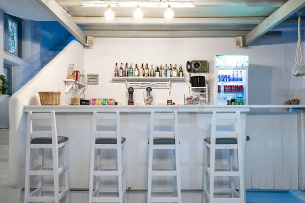 Barbereich des Iris Boutique Hotels mit weißen Stühlen und Theke.