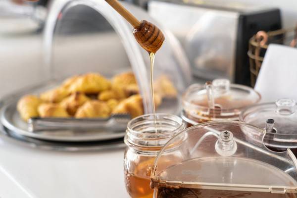 Ein Honigtopf wird über Frühstücksgebäck im Iris Boutique Hotel gegossen.
