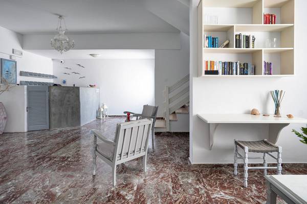 Innenbereich des Iris Boutique Hotel mit Marmorboden, weißen Möbeln, Bücherregal und Treppe.