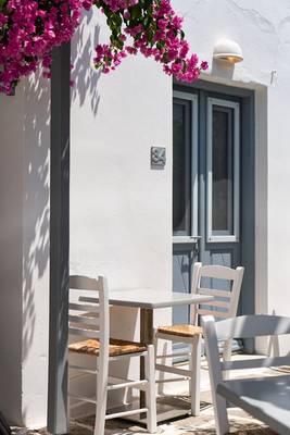 Außenterrasse des Iris Boutique Hotels mit weißen Stühlen und Tisch unter blühenden Bougainvillea.