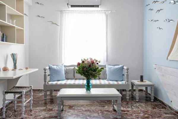Wohnzimmer des Iris Boutique Hotels mit heller Einrichtung, Blumenvase, Sofa und offenem Fenster.