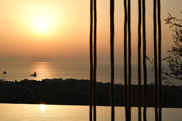 Sonnenuntergang am Meer vom Mythic Hotel aus gesehen, mit Blick auf eine Stadt und zwei kleine Inseln.