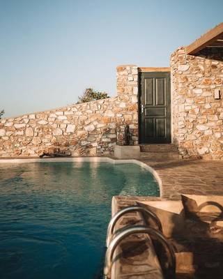 Außenbereich des Mythic Hotels mit einem Pool und einer Steinmauer