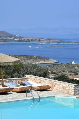 Mythic Hotel mit Blick auf das Meer und Inseln, Pool mit Liegen und Sonnenschirm.