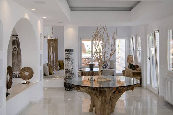 Innenraum des Mythic Hotels mit weißem Design, großen Glastischen und architektonischen Elementen.