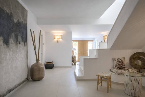 Der Flurbereich des Mythic Hotels mit weißen Fliesen, einer Treppe und einer Lampe.