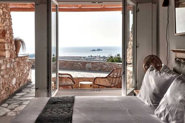 Schlafzimmer im Mythic Hotel mit offenem Fenster und Meerblick.