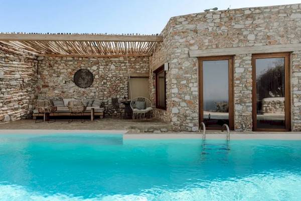 Außenbereich des Mythic Hotels mit Pool, Steinmauer und Möbeln
