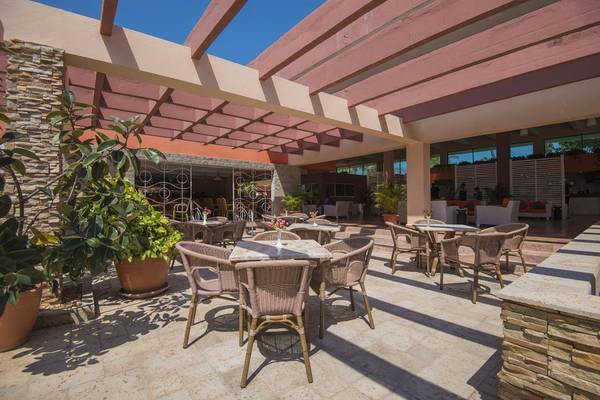 Außenterrasse des Gran Caribe Villa Tortuga Hotels mit Tischen, Stühlen und Pflanzen.