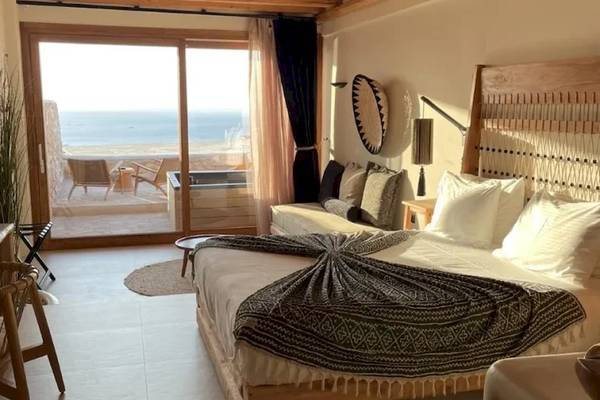Mythic Hotel Zimmer mit Meerblick, großes Bett und Blick auf Terrasse mit Strand