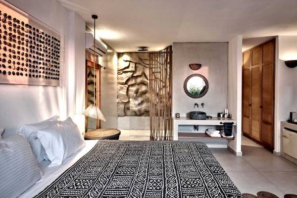 Innenansicht des Schlafzimmers im Mythic Hotel mit Doppelbett, Wandkunst und Badbereich.