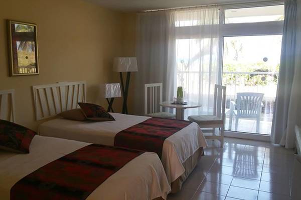 Doppelzimmer im Gran Caribe Villa Tortuga Hotel mit zwei Betten, Tisch, Lampen und einem Balkon.