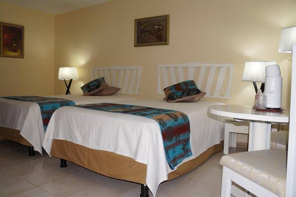 Doppelzimmer im Gran Caribe Villa Tortuga Hotel mit zwei Betten, Tisch, Stühlen und Lampen.