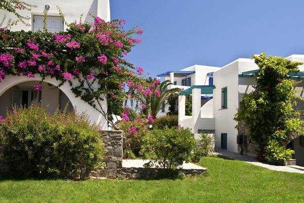 Außenansicht des Poseidon of Paros Hotel & Spa mit weißen Gebäuden und bunten Blumen.