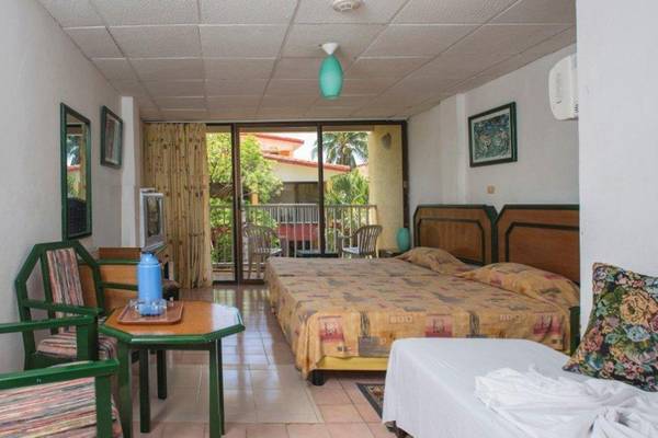 Hotelzimmer im Gran Caribe Villa Tortuga mit zwei Betten, Balkon und Möbeln.