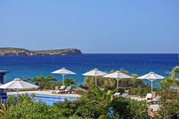 Außenbereich des Poseidon of Paros Hotel & Spa mit Pool, Sonnenschirmen und Meerblick