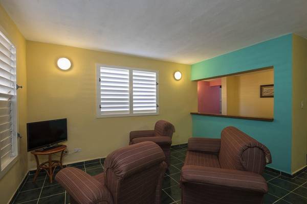 Wohnzimmer im Gran Caribe Villa Tortuga Hotel mit Fernseher und Sesseln.