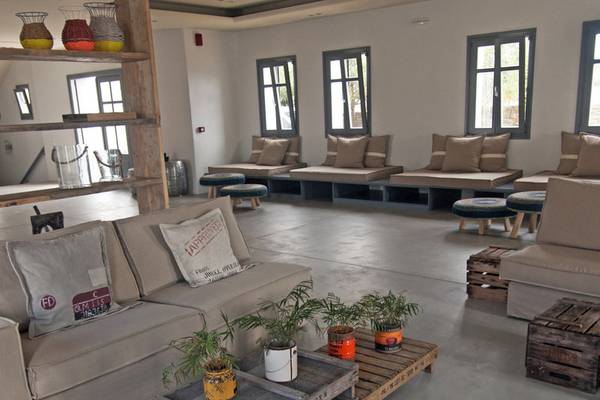 Poseidon of Paros Hotel & Spa Lounge mit Sofas, Kissen, Tischen und Pflanzen.