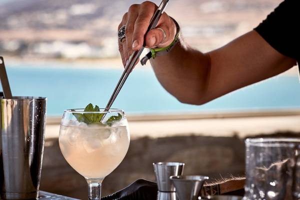 Ein Barkeeper bereitet einen Cocktail im Poseidon of Paros Hotel & Spa zu, mit Blick auf das Meer.