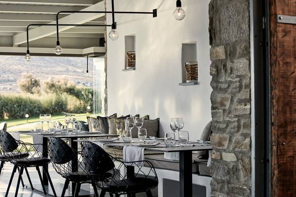 Innenansicht des Poseidon of Paros Hotel & Spa Restaurants mit Tischen und Stühlen.