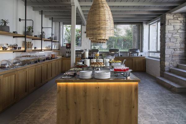 Frühstücksbereich im Poseidon of Paros Hotel & Spa mit Buffet und Holzmöbeln.