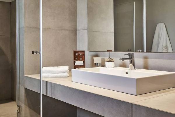 Badezimmer des Poseidon of Paros Hotel mit einer Dusche, einem Waschbecken und Handtüchern.