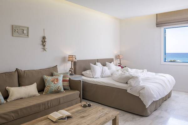 Schlafzimmer im Poseidon of Paros Hotel & Spa mit Meerblick, Doppelbett und Sofa.