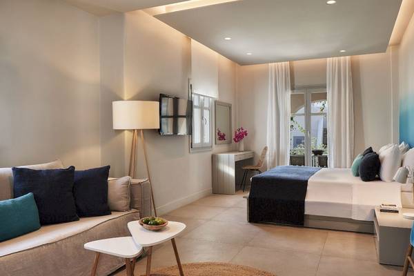 Innenansicht des Schlafzimmers im Poseidon of Paros Hotel & Spa mit Bett, Sofa, Tisch und Balkonzugang