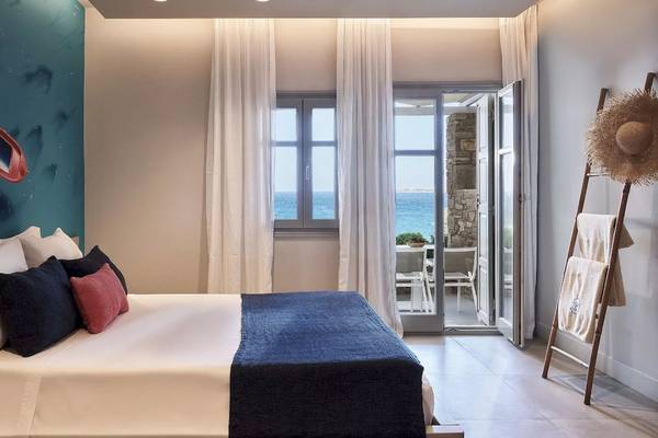 Schlafzimmer im Poseidon of Paros Hotel & Spa mit Blick auf das Meer und eine offene Terrasse.