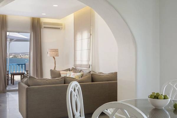 Innenansicht des Poseidon of Paros Hotel & Spa mit einem Wohnzimmer, einer Couch, einem Tisch und Blick aufs Meer.