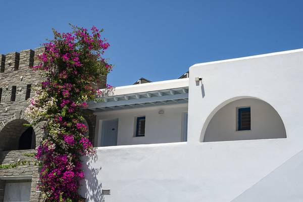 Außenansicht des Pyrgaki Hotels mit weißen Wänden und blühenden Bougainvillea-Pflanzen.