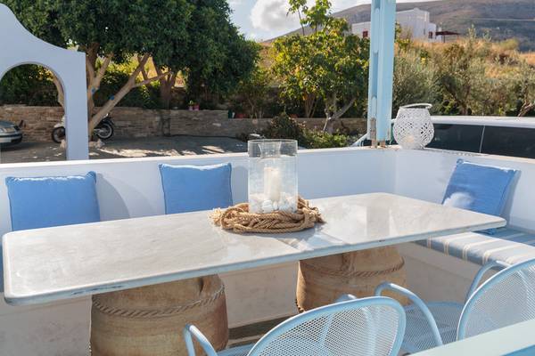 Außenansicht der Terrasse des Pyrgaki Hotels mit Tisch, Stühlen und Kissen.