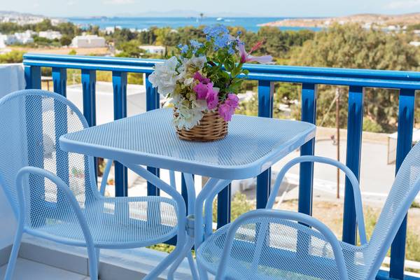 Ein Balkon mit Blumen auf einem Tisch und zwei Sesseln im Pyrgaki Hotel.