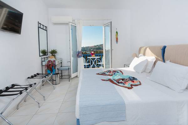 Schlafzimmer im Pyrgaki Hotel mit Blick auf einen Balkon und eine Terrasse.