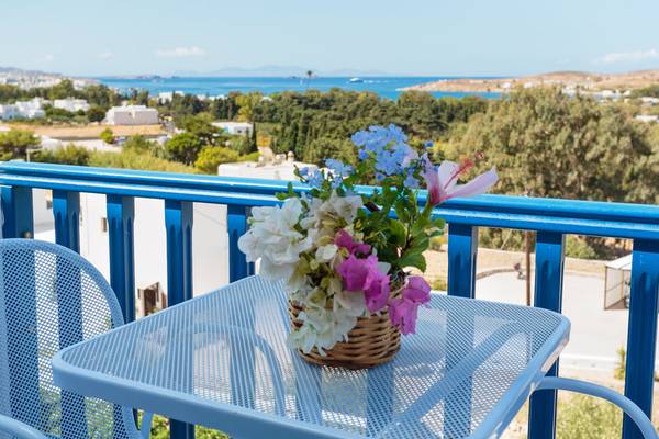 Balkon mit blauem Geländer und Blick auf das Meer, Blumen in einem Korb auf einem Tisch