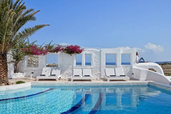 Außenpool des Mr and Mrs White Paros Hotels mit weißen Liegestühlen und Palme