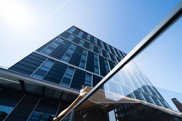 Ein modernes Hochhaus mit Glasfassade unter blauem Himmel.