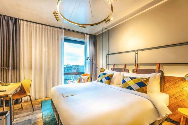 Schlafzimmer im Four Elements Hotel Amsterdam mit Bett, Fenster und Blick auf die Stadt.