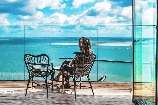 Frau auf dem Balkon des Four Elements Hotel Amsterdam mit Blick auf das Meer