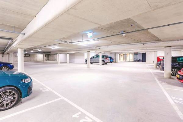 Unterirdischer Parkplatz im Four Elements Hotel Amsterdam mit mehreren geparkten Autos.