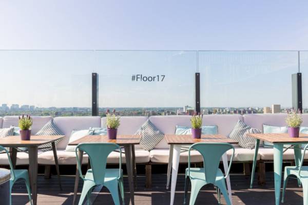 Terrasse im Leonardo Hotel Amsterdam Rembrandtpark mit Tischen, Stühlen und Pflanzen.